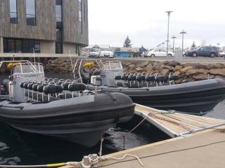 Two RIB boats, docket at a pier in front of big round building called Hof.