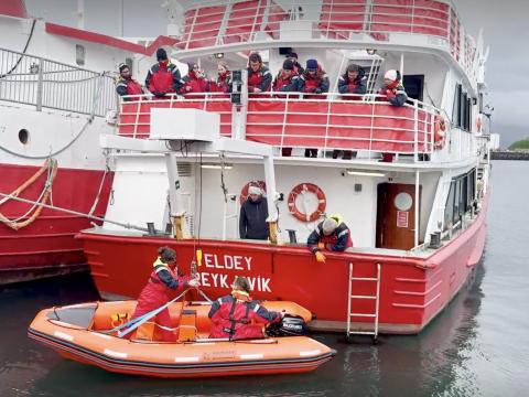 MOB exercise with the Elding team, crew stands at the back of the boat as the MOB boat is lowered into the sea.