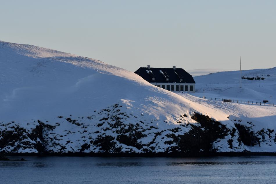 Viðey House hiding behind a snowy hill on Viðey island