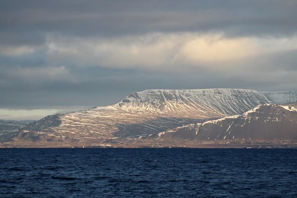 snowy mountains in reykjavik against dark blue seas